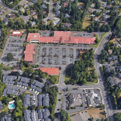 An overhead shot of a shopping center, showing parking lots and adjacent streets