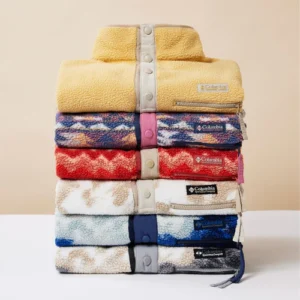A stack of multi-colored fleece Columbia jackets on a white counter