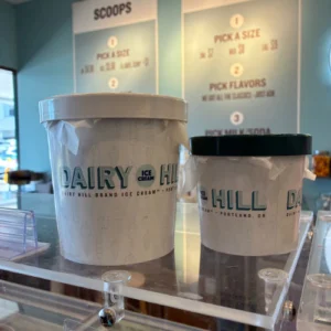 A larger and smaller container with "Dairy Hill" on them sit on a plexiglass case