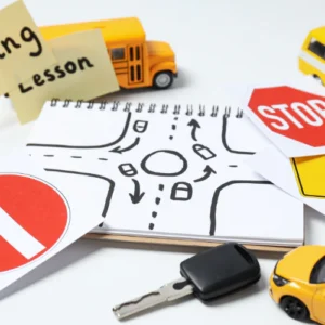 A sketch pad showing a round-a-bout is surrounded by keys, signs, notes, and a mini school bus